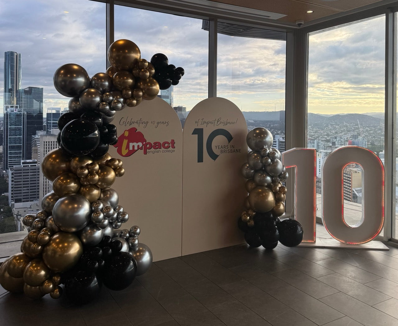 Decorative balloon arch with 'Impact' branding in front of a cityscape view.