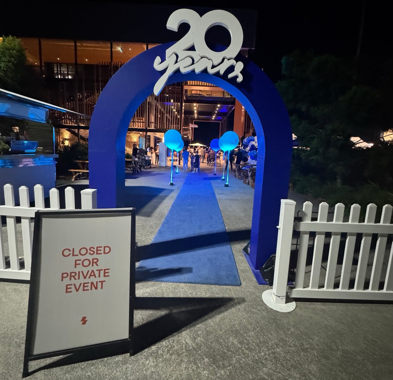 Blue arch with '20 years' sign at a private event entrance