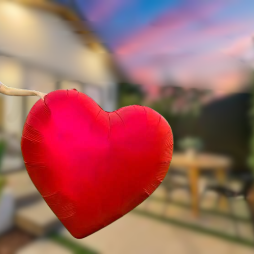 Red heart-shaped balloon against a blurred outdoor background